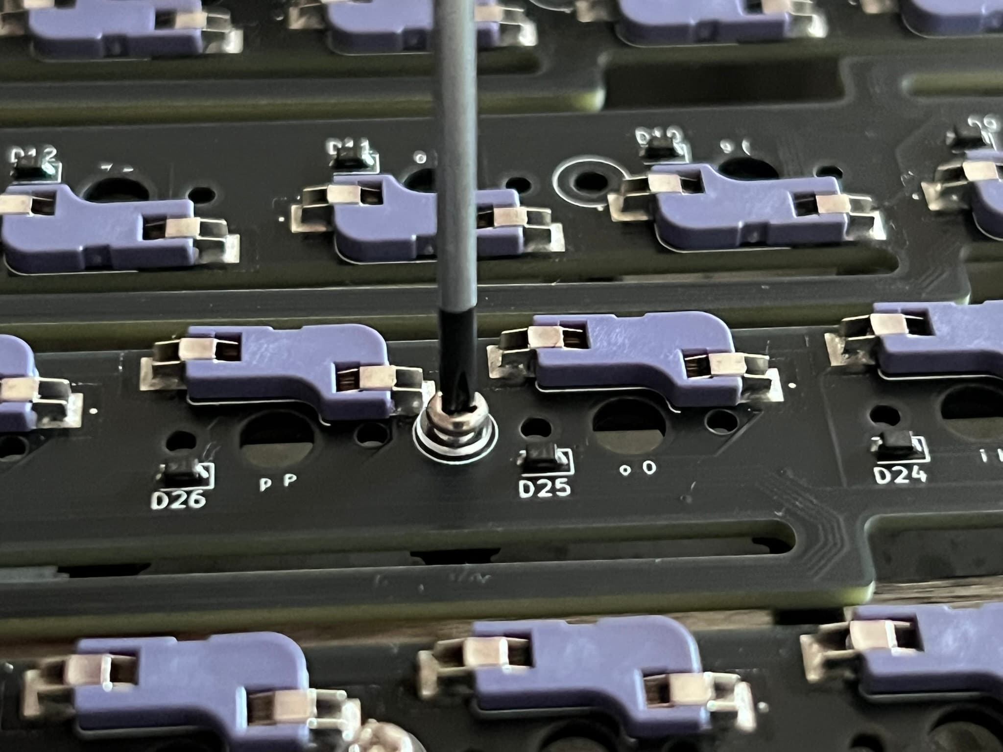 Screwdriver on screw on washer on PCB on standoff on plate