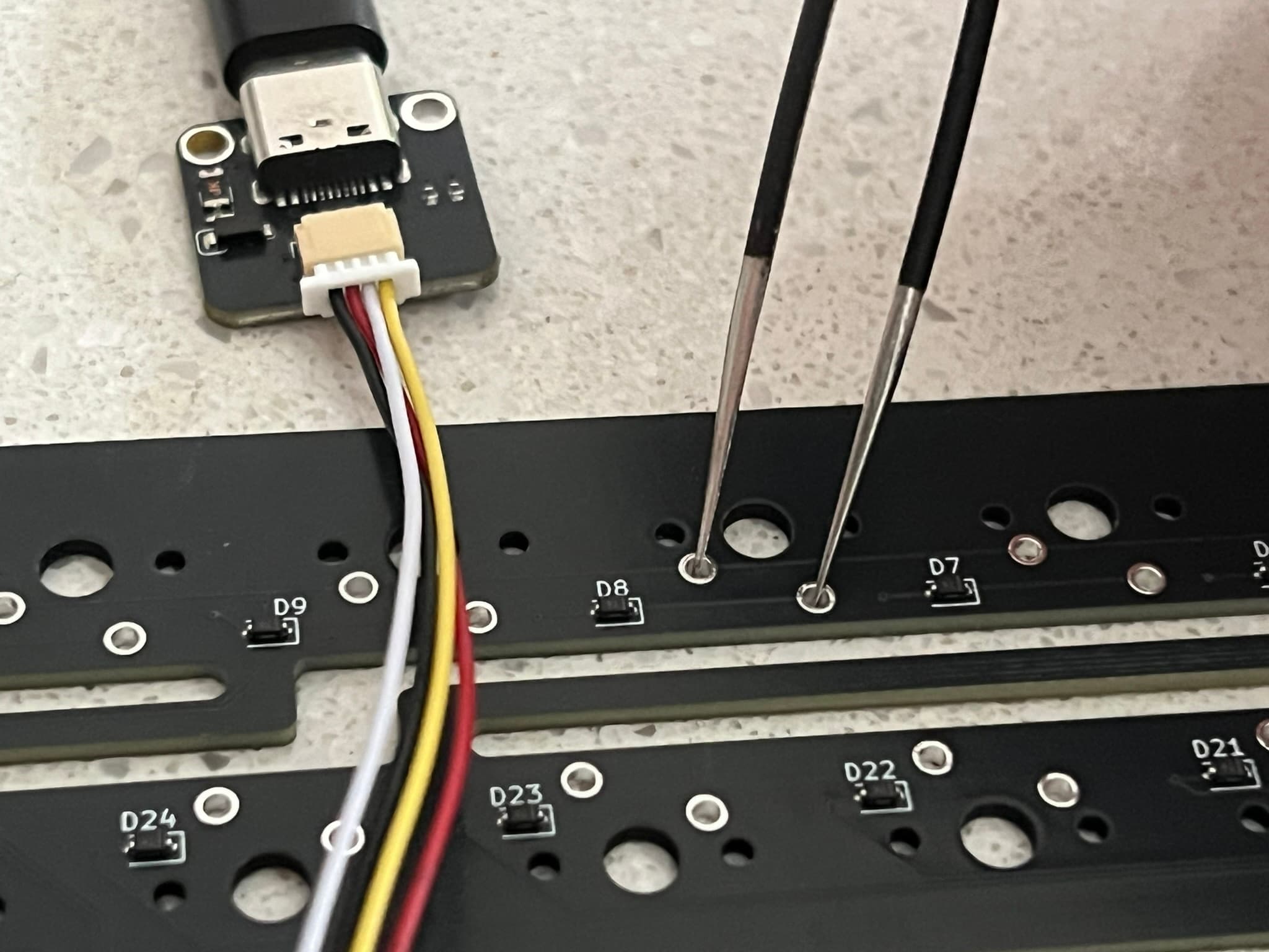 Tweezers shorting two switch holes on a PCB