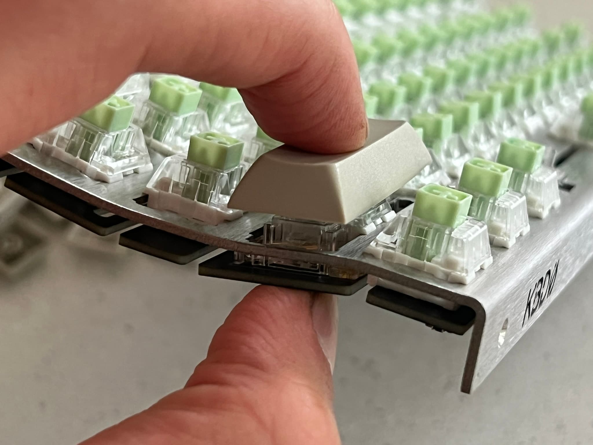 Thumb supporting PCB from the bottom while index finger pushes keycap onto left shift switch and stabilizer